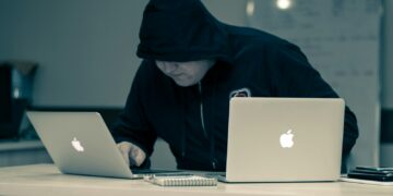 man in black hoodie using macbook