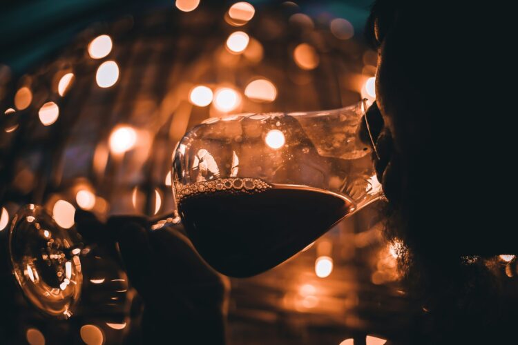 Person holding wine glass with red wine
