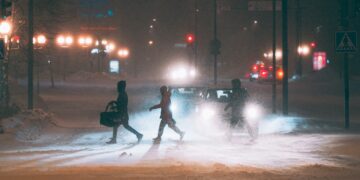 a group of people walking across a snow covered street