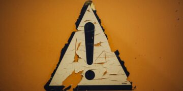 a triangle shaped sign on a yellow wall