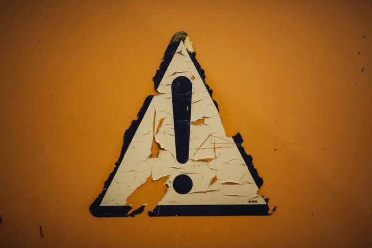 A triangle shaped sign on a yellow wall