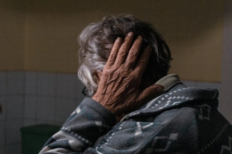 An older woman covering her face with her hands