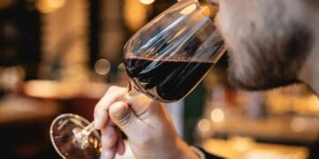 a man drinking a glass of red wine