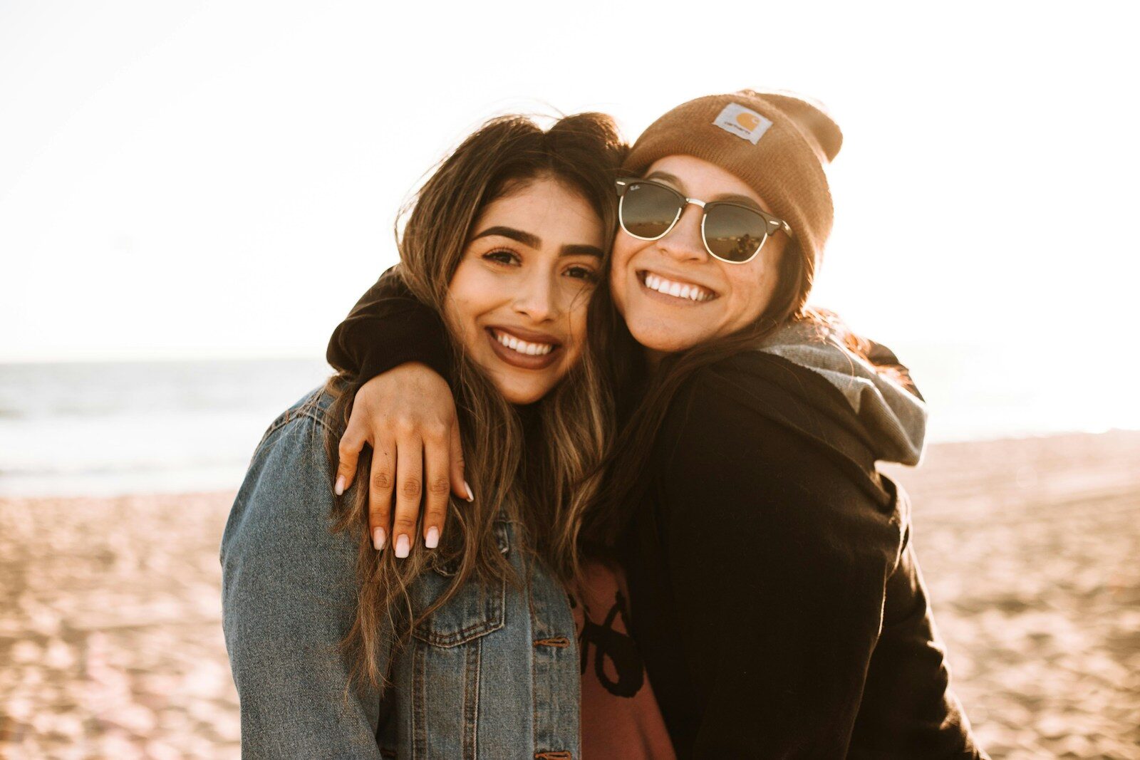 Photo by Omar Lopez - Info Vandaag Woman hugging other woman while smiling at beach