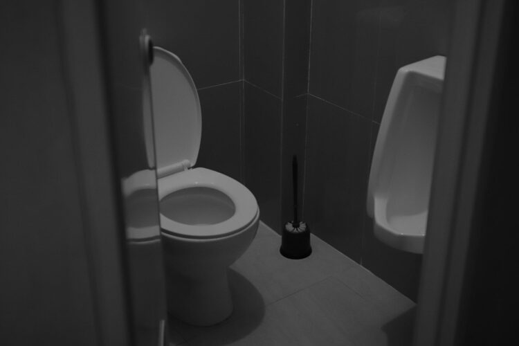 A white toilet sitting next to a urinal in a bathroom