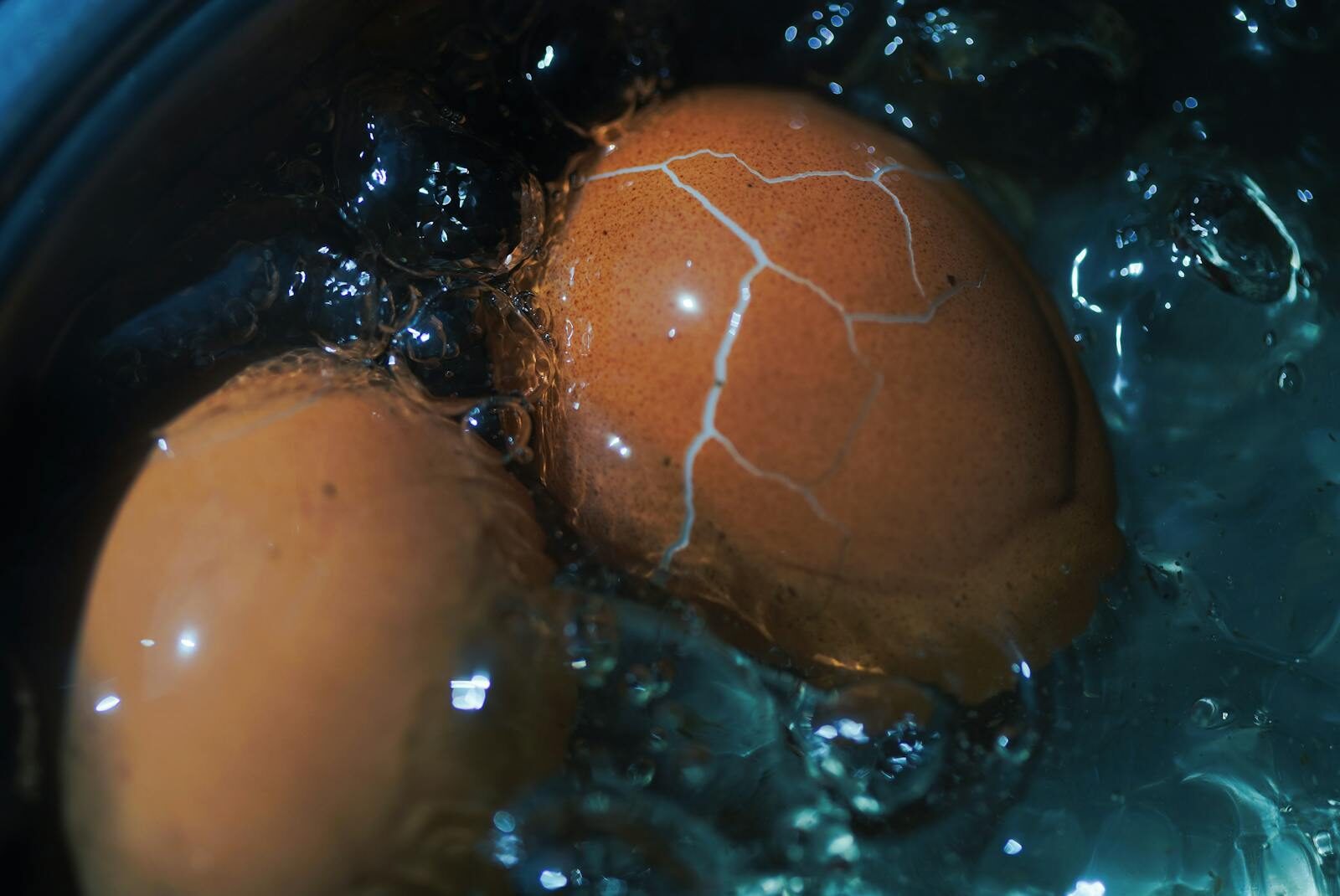 Close up view of a cracked brown egg boiling in water showcasing texture and cooking process