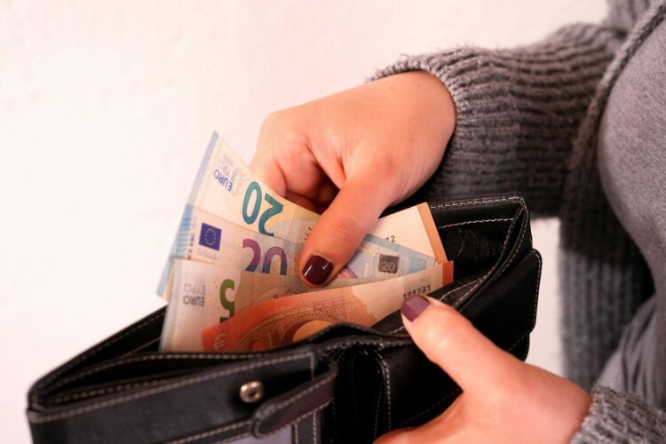 A woman is holding a wallet full of money