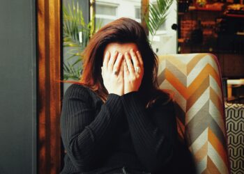 Woman in black long sleeve shirt covering her face