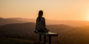 woman sitting on bench over viewing mountain