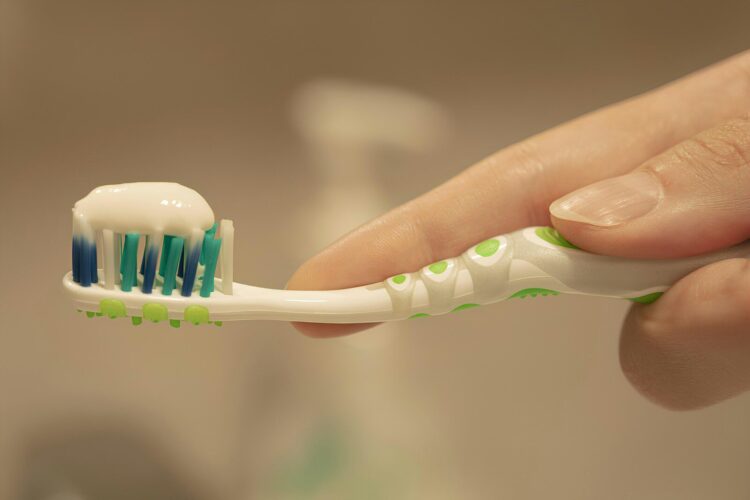 A person is holding a toothbrush with toothpaste on it