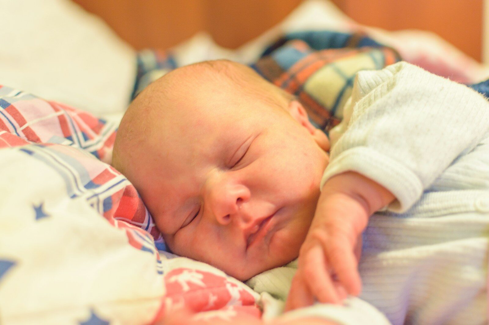 Baby in white and blue onesie lying on bed