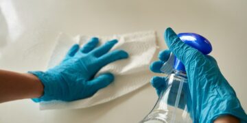 Person holding blue textile near clear glass bottle
