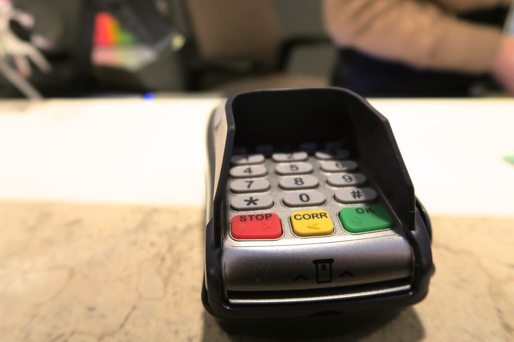 Card payment terminal with red stop yellow corr and green ok buttons on a counter edge