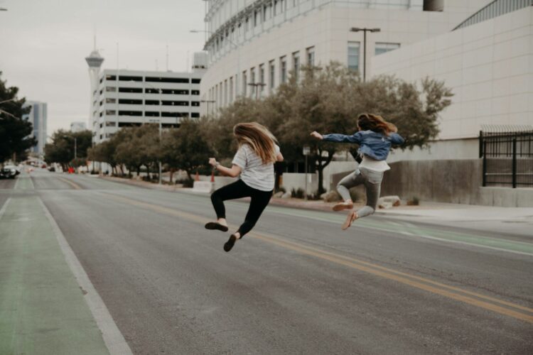 Two woman jumping on the street during daytime