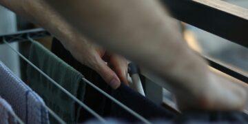 Hands arranging clothes on a drying rack.