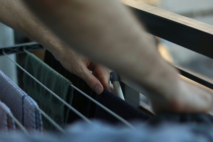 Hands arranging clothes on a drying rack