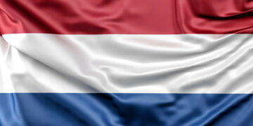 Waving flag of the Netherlands with horizontal red, white, and blue stripes on fabric.