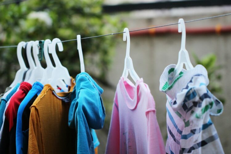 Pink and blue clothes hanging on brown wooden cabinet