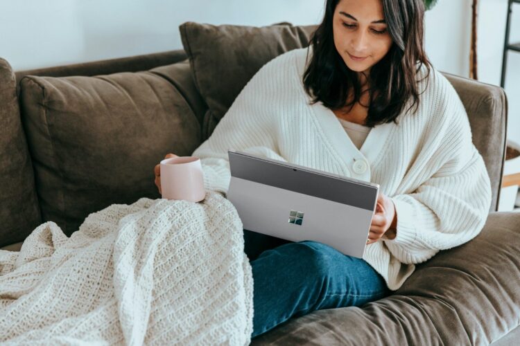 A woman sitting on a couch holding a laptop