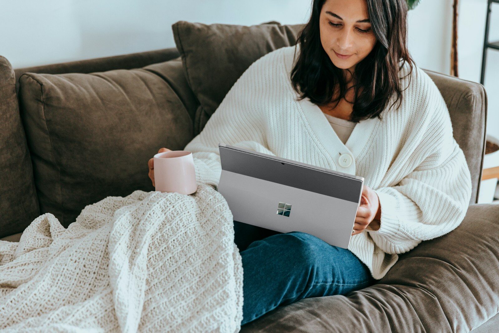 A woman sitting on a couch holding a laptop