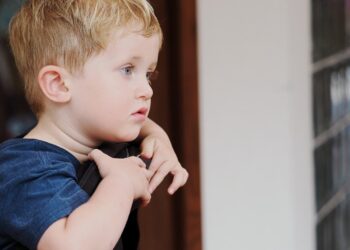 Young boy with blond hair looking out window