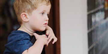 Young boy with blond hair looking out window