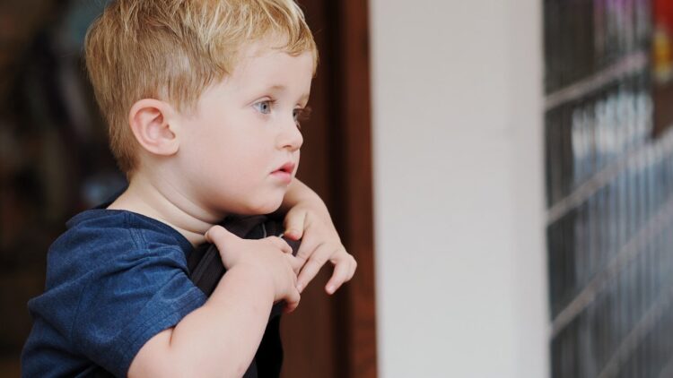 Young boy with blond hair looking out window