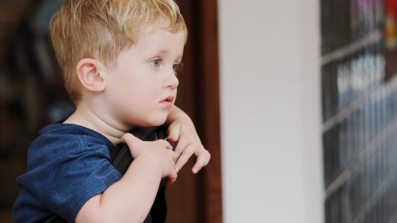 Young boy with blond hair looking out window