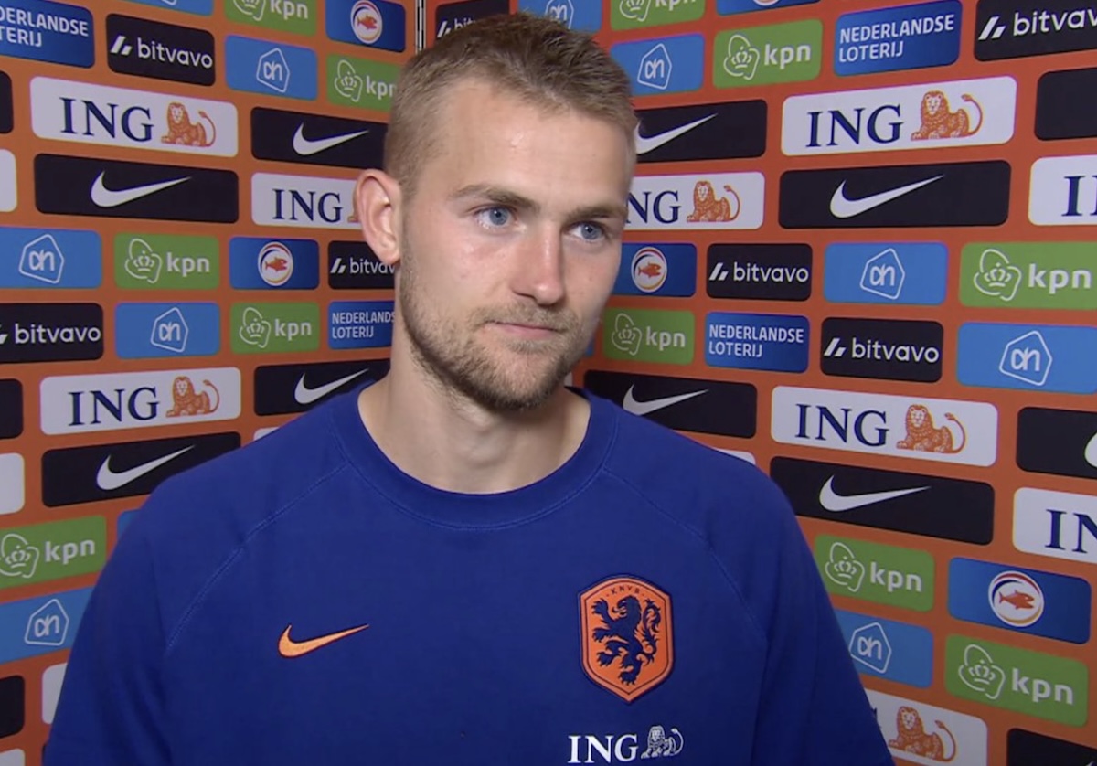 Portrait of a dutch footballer in a blue netherlands jersey standing before a sponsor wall full of ing and nike logos