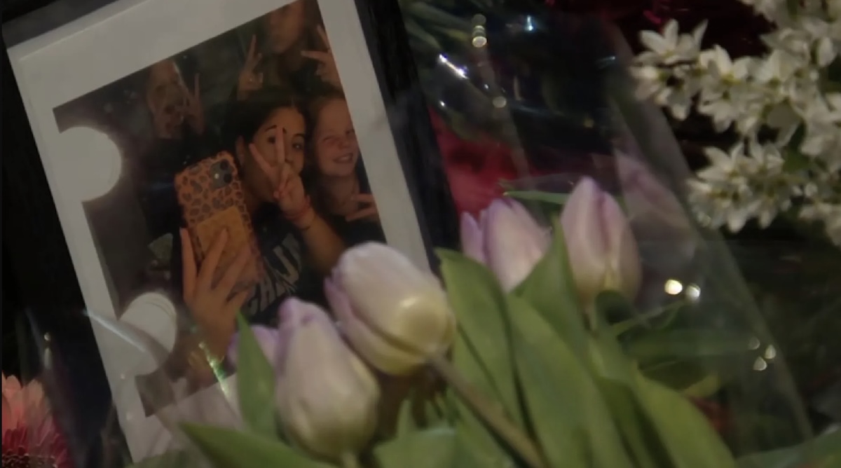 Framed photo of two girls flashing peace signs partially obscured by a bouquet of pale pink tulips in the foreground