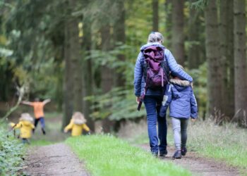 Woman in blue denim jeans and black jacket walking with woman in green jacket