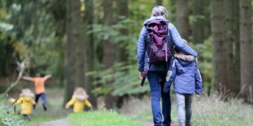 woman in blue denim jeans and black jacket walking with woman in green jacket