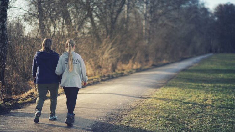 Woman in white jacket and black pants walking on road during daytime