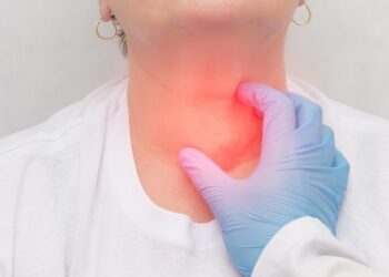 Medical professional in a blue glove pressing a patients throat with a red glow indicating neck pain area