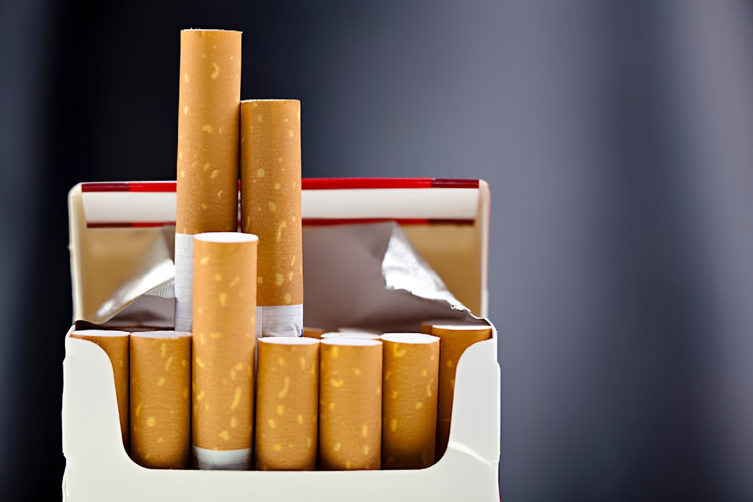 Open cigarette pack with several brown cigarettes standing upright inside