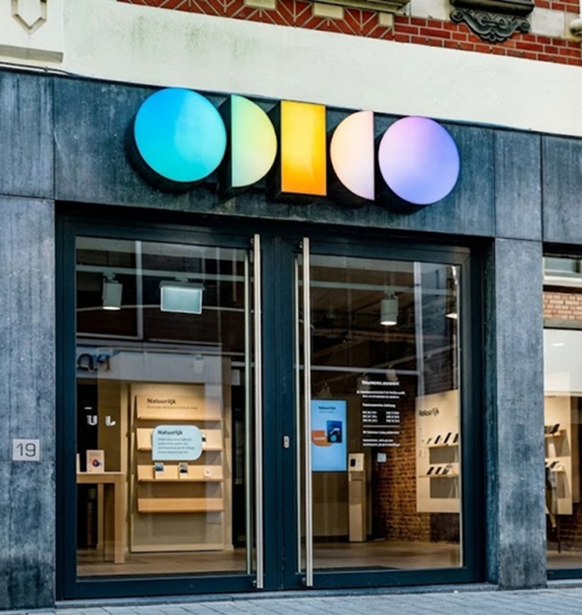 Storefront with a multicolored circular letter sign reading 'odilo' above glass double doors