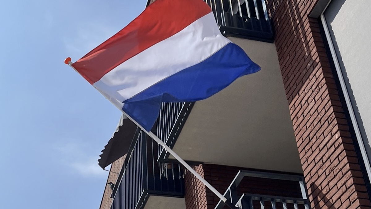 Dutch flag fluttering from a balcony on a brick apartment building outside view