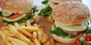 burger with lettuce and fries on brown wooden table