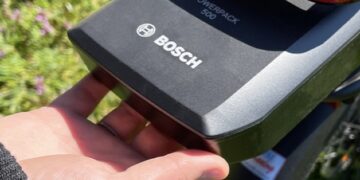 Close-up of a hand lifting the Bosch PowerPack 500 e-bike battery on a bike outdoors.