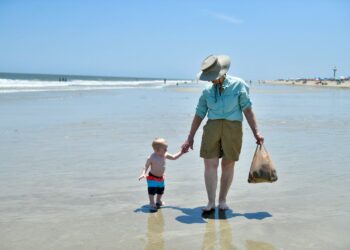 a woman and a child are walking on the beach