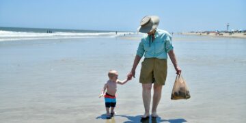a woman and a child are walking on the beach