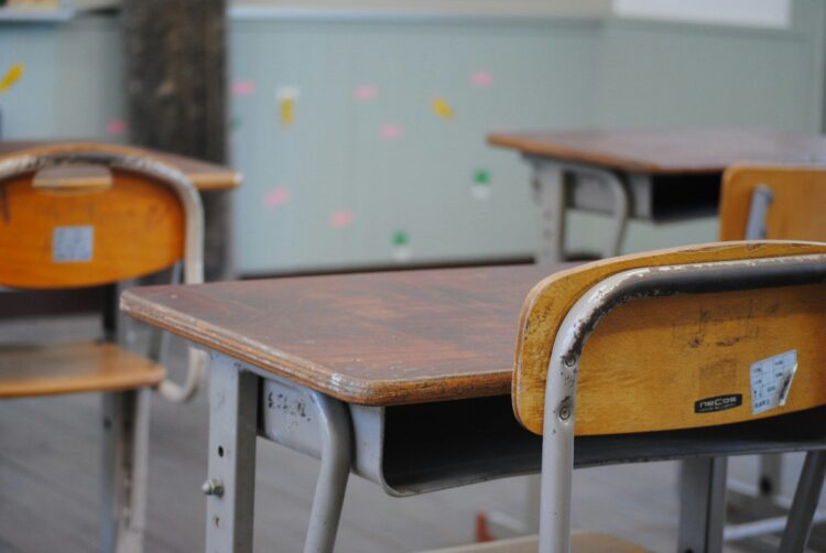 A row of wooden school desks in a classroom