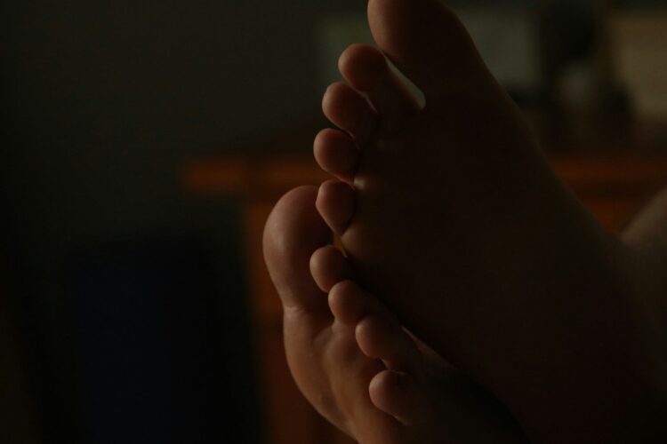 Close-up of bare feet in dim lighting.