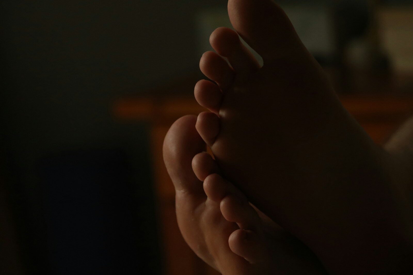 Close-up of bare feet in dim lighting.