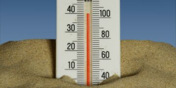 A thermometer in the sand with a blue sky in the background