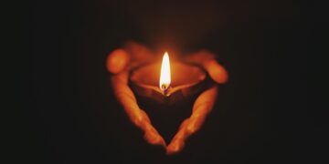person holding lighted oil lamp
