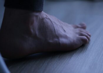 A bare foot resting on a wooden floor.