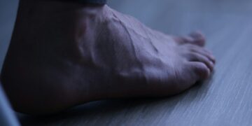 A bare foot resting on a wooden floor.