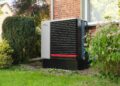 Outdoor heat pump unit next to a brick building.