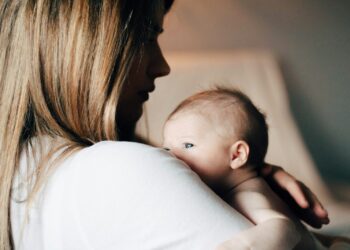 woman in white shirt carrying baby
